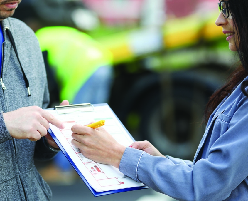 Woman signing claim paperwork from her auto insurance adjustor