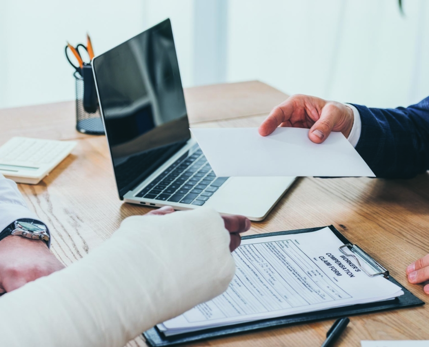 Person with an arm cast accepting a workers' compensation claim payment from an insurance professional