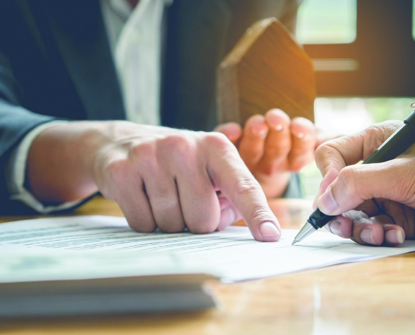 Close up view of professional pointing out a spot for client to sign a contract