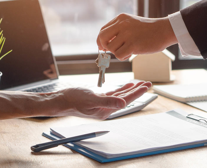 close up view of landlord handing tenant keys after signing lease contract