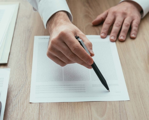 close up view of man behind desk pointing out signature line on contract