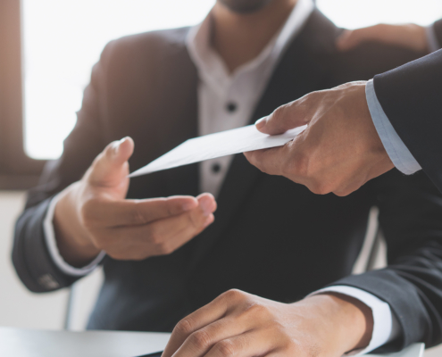 close up view of man patting client's shoulder and handing him an envelope