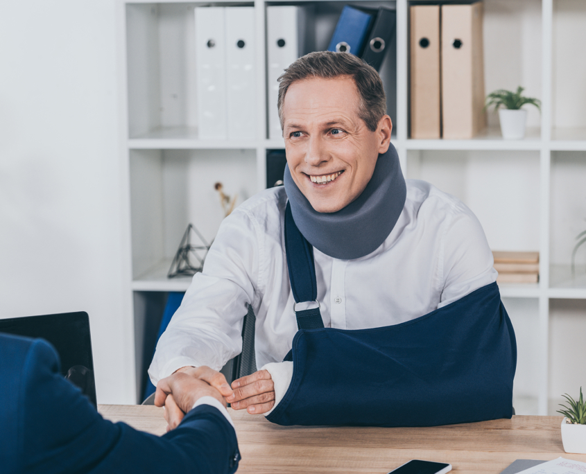 smiling man with arm sling and neck brace shaking claim adjuster's hand