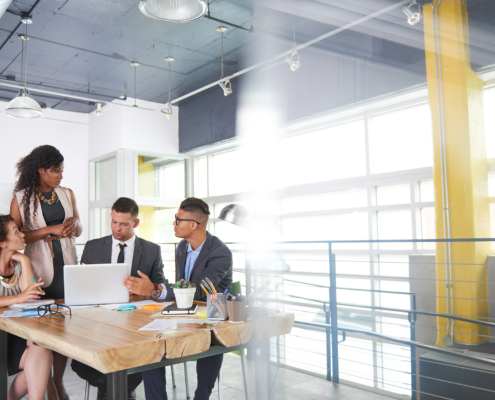 Four coworkers chatting at a table in industrial office setting