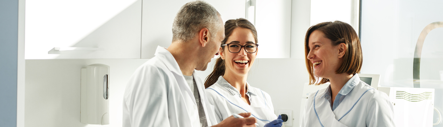 Dentist and two hygienists smiling and discussing test results in a medical office