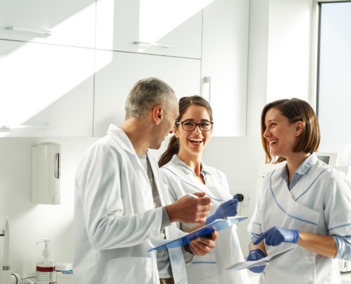 Dentist and two hygienists smiling and discussing test results in a medical office