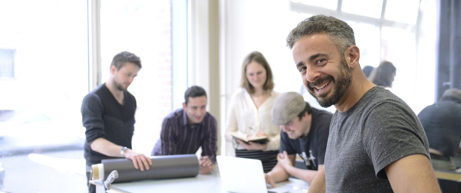 Professionals in Business Meeting as Owner Smiles at Camera